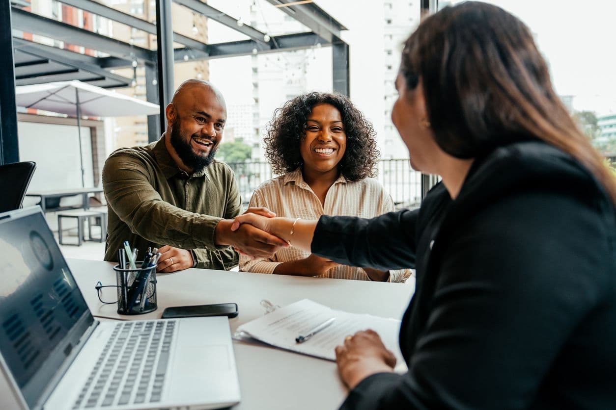 A group of professionals shaking hands during a meeting focused on job pay discussions.